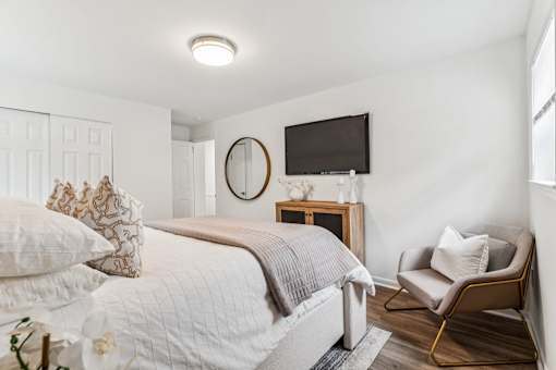 A bedroom with a bed, chair, and a mirror.