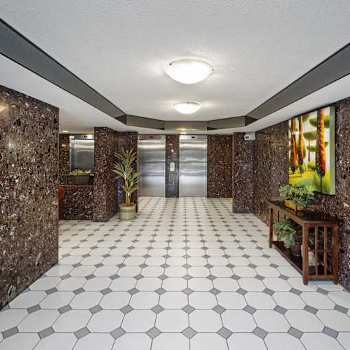 a lobby with a white tile floor and marble walls