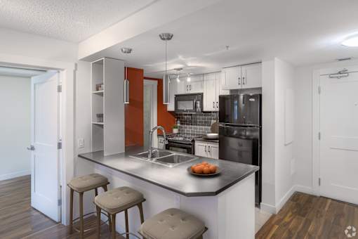 A kitchen with a black countertop and white cabinets.
