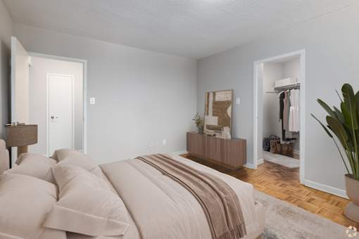 A bedroom with a large bed and a wooden dresser.