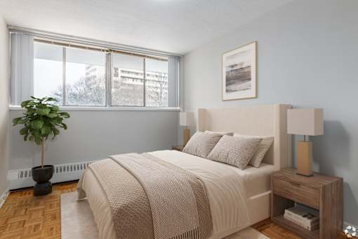 A bedroom with a large bed and a potted plant.