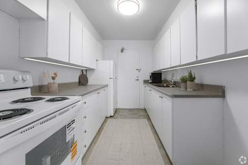 A white kitchen with a stove and a refrigerator.