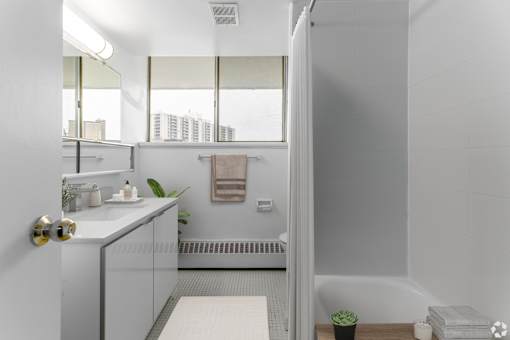 A white bathroom with a window and a sink.