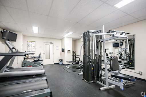 A gym with treadmills, weights, and exercise equipment.