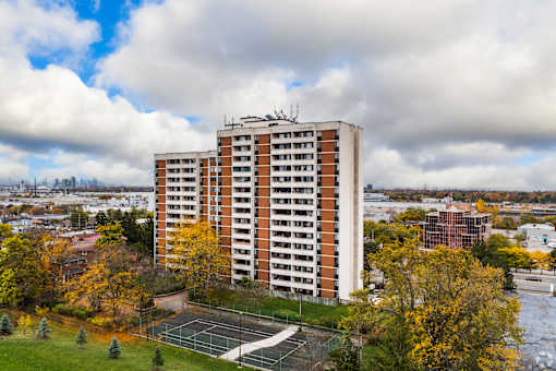 A tall apartment building with a tennis court in front of it.