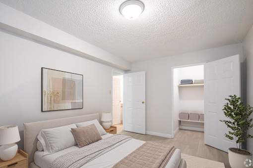 A bedroom with a bed, nightstand, and a plant.