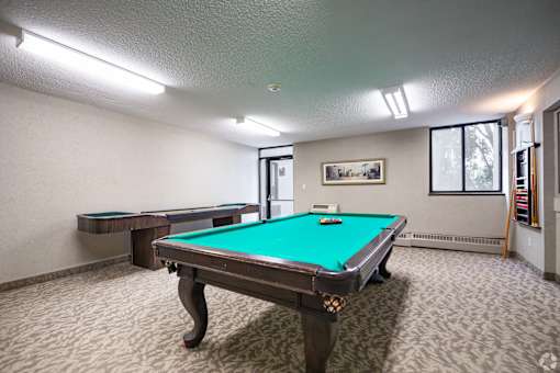 A pool table in a room with a picture on the wall.