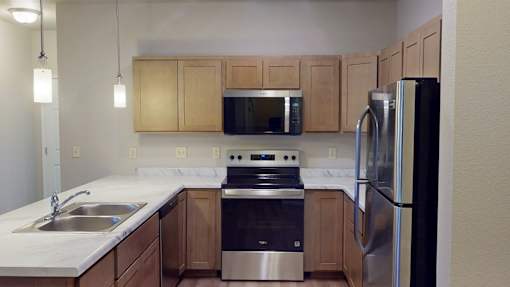 A kitchen with a stainless steel refrigerator, sink, and stove.