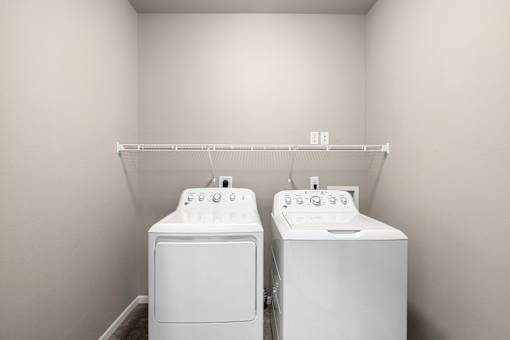 Two white front loading washing machines in a laundry room.