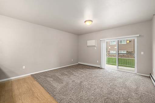 A room with a carpeted floor and a sliding glass door leading to a backyard.