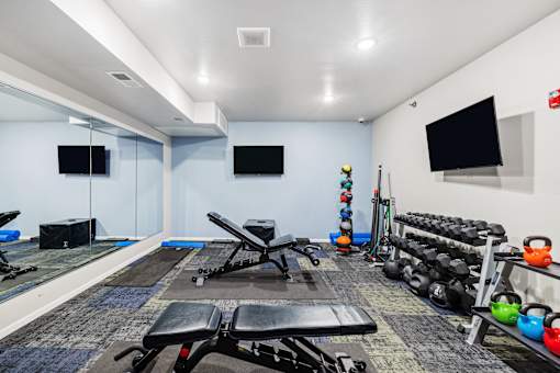 A gym with a variety of equipment including weights and exercise machines.