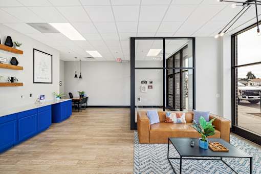 A modern office lobby with a blue reception desk and a brown sofa.