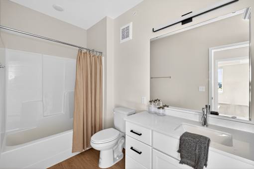 A white bathroom with a toilet, sink, and shower.