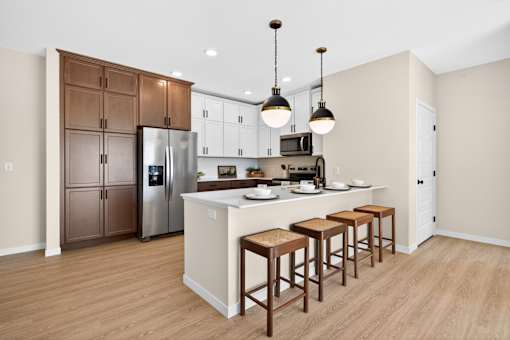 A kitchen with a refrigerator, cabinets, and a counter.