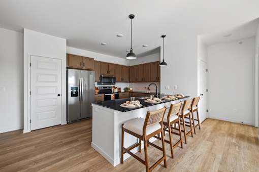 A kitchen with wooden chairs and a black countertop.