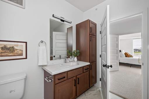 A bathroom with a white sink and brown cabinet.