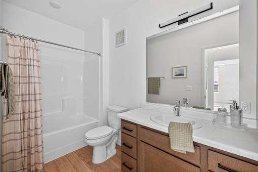 A bathroom with a toilet, sink, and mirror.