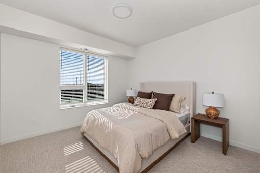 A bedroom with a large bed and a window with blinds.