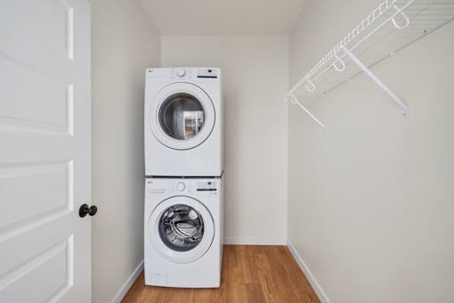 A white dryer and washer are stacked on top of each other in a small room.