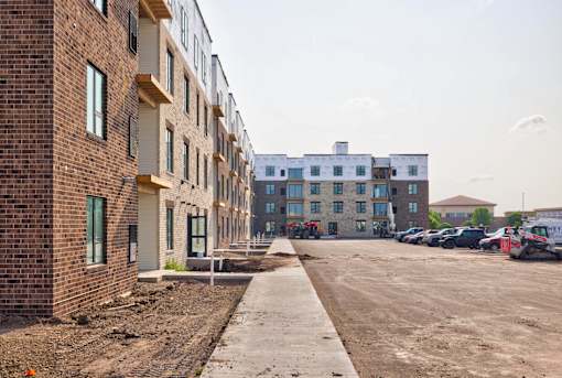 A construction site with a row of unfinished buildings on the left and a row of finished buildings on the right.