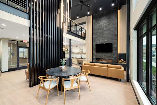 A black table with four chairs in front of a fireplace.