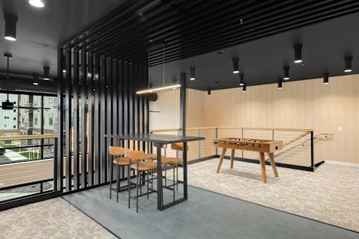 A room with a table and chairs and a shelf with a lamp.