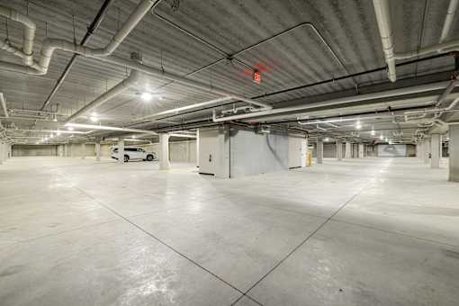 A large, empty parking garage with a concrete floor and white walls.