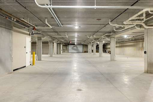 A large, empty, industrial-style room with white walls and a concrete floor.