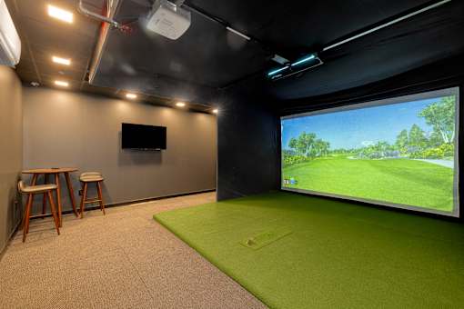 A room with a green carpet and a large screen on the wall.