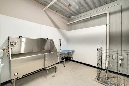 A large industrial metal container is in a room with a table and a fence.