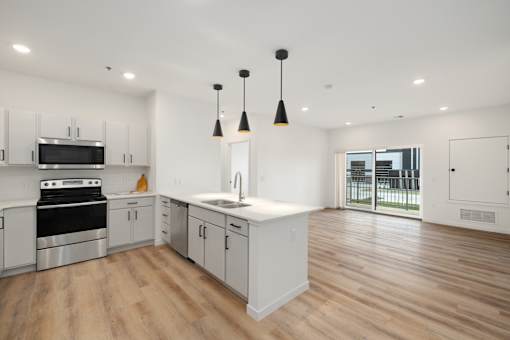 A kitchen with white cabinets and a wooden floor.