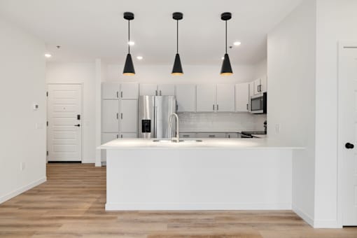 A kitchen with a white island and pendant lights.