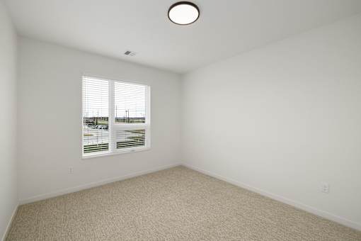 A room with a window and a carpeted floor.
