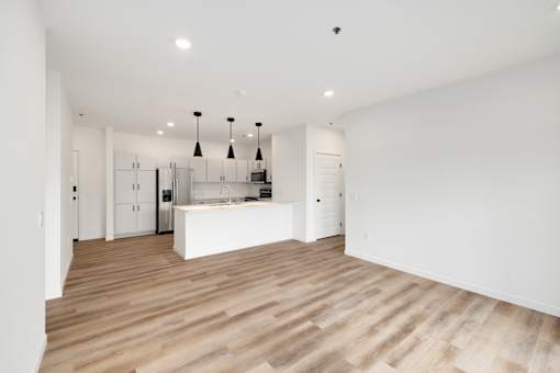 A kitchen with a white counter and wooden floors.