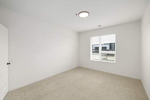 A white room with a window and a carpet on the floor.