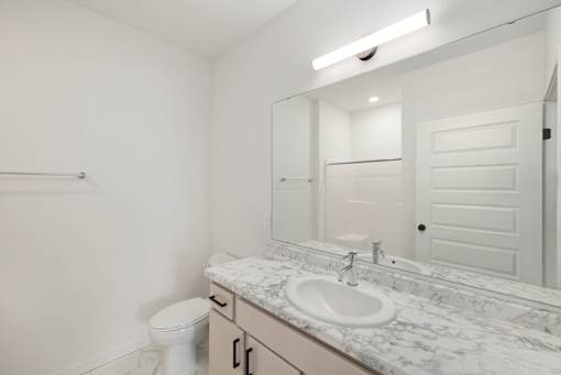 A white bathroom with a toilet, sink, and mirror.