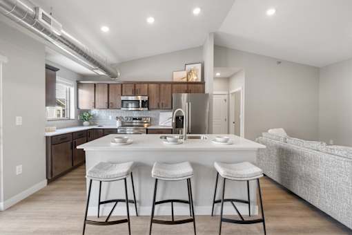 A modern kitchen with a bar stool in front of the island.