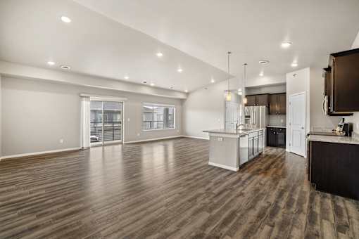 A spacious kitchen with a wooden floor and white walls.