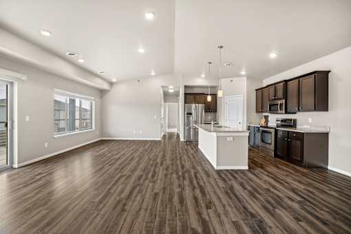 A spacious kitchen and living room with wood flooring and modern appliances.