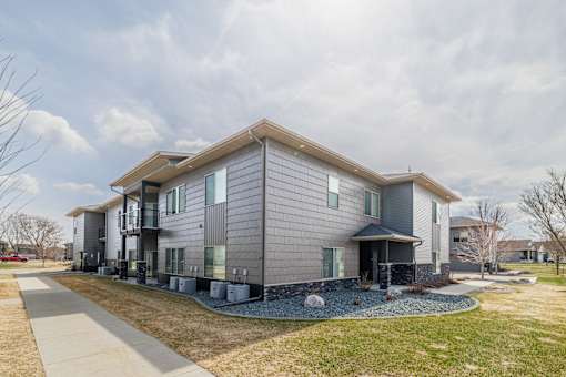 A modern house with a grey facade and a stone pathway leading to the entrance.