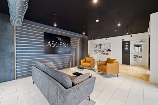 A room with a sofa and two lounge chairs and sign that says The Ascent.