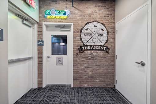 A door with a sign next to it that says The Ascent Clubhouse