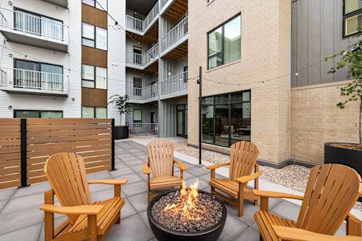 A fire pit sits in the middle of a patio surrounded by chairs.