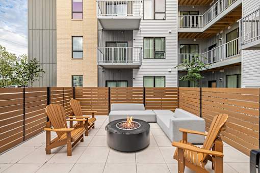 A patio with a fire pit, chairs and a couch.