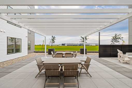 A patio with a table and chairs is covered by a white roof.