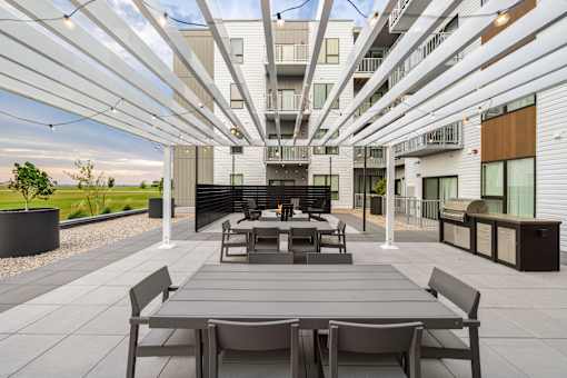 A modern outdoor seating area with a long table and chairs.