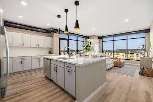 A modern kitchen with a large island and pendant lights.