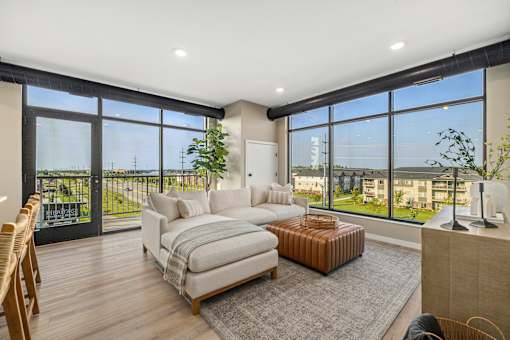 A living room with a couch, a chair, and a large window overlooking a balcony.