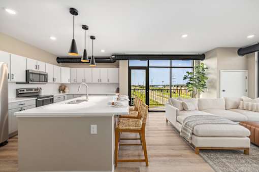 A modern kitchen with a large island and a dining area with a view.