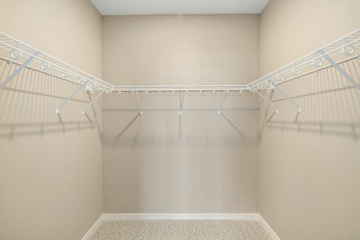 Empty white walk in closet with shelves.